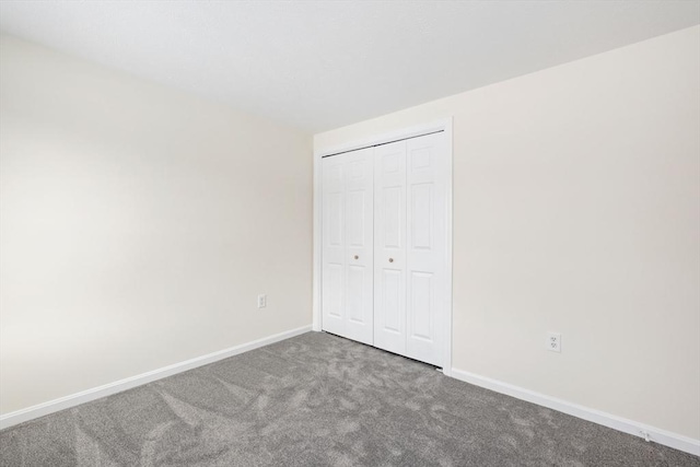 unfurnished bedroom with a closet, carpet flooring, and baseboards