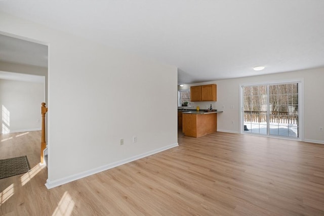 unfurnished living room with light wood-style floors and baseboards