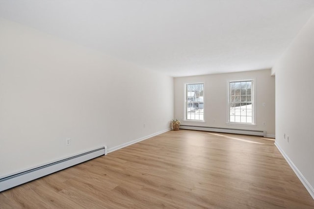 unfurnished room with baseboards, a baseboard radiator, and light wood-style floors