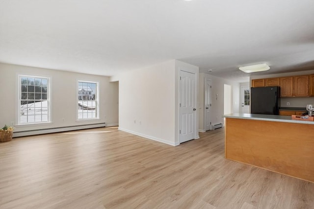 kitchen featuring a baseboard radiator, light wood-style floors, freestanding refrigerator, open floor plan, and brown cabinetry