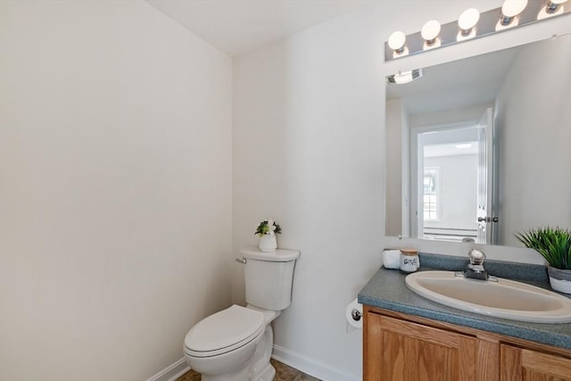 half bathroom with toilet, baseboards, and vanity