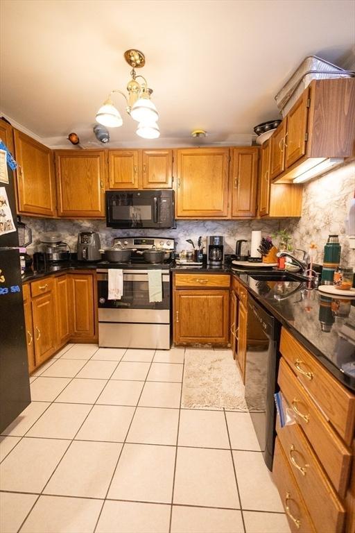 38 Carter St Unit 303, Everett, MA 02149 - kitchen featuring black appliances, dark countertops, brown cabinets, light tile patterned flooring, and backsplash