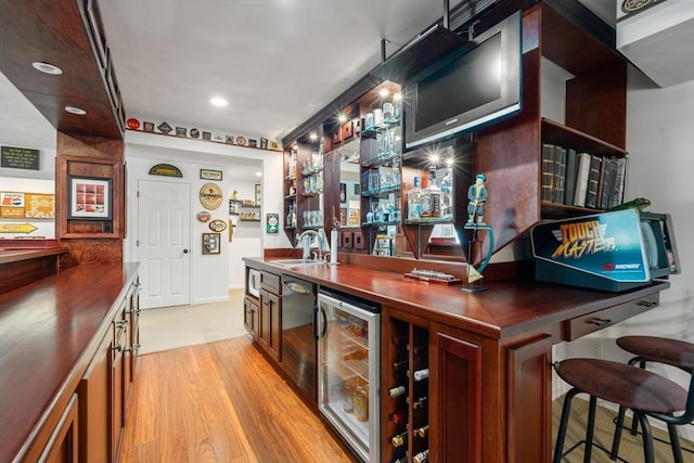 bar featuring wine cooler, sink, and light hardwood / wood-style flooring