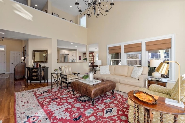 living room featuring hardwood / wood-style floors, a towering ceiling, and a notable chandelier