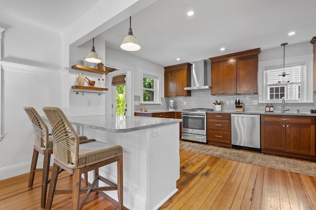 614 Summer St, Arlington, MA 02474 - kitchen with stainless steel appliances, wall chimney range hood, backsplash, light wood finished floors, and a breakfast bar area