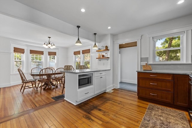 614 Summer St, Arlington, MA 02474 - kitchen featuring stainless steel microwave, hardwood / wood-style floors, a peninsula, a chandelier, and hanging light fixtures