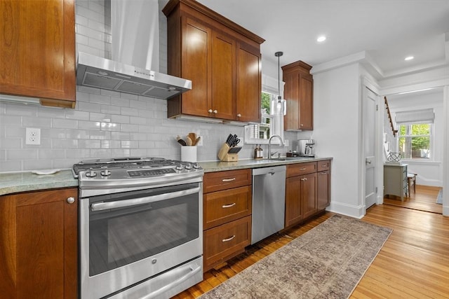 614 Summer St, Arlington, MA 02474 - kitchen with appliances with stainless steel finishes, wall chimney range hood, tasteful backsplash, light wood finished floors, and brown cabinetry