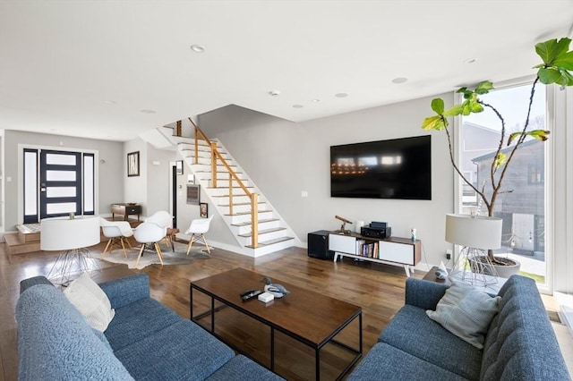 living area featuring baseboards, stairs, and wood finished floors
