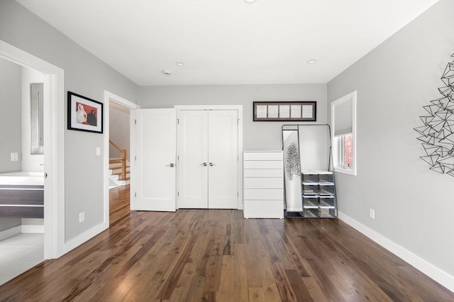 unfurnished bedroom featuring baseboards, wood finished floors, and a closet