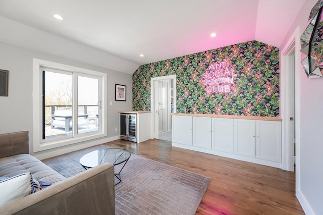 living room with wallpapered walls, vaulted ceiling, wood finished floors, and wine cooler