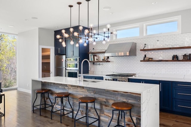 kitchen featuring open shelves, decorative backsplash, extractor fan, blue cabinets, and a sink
