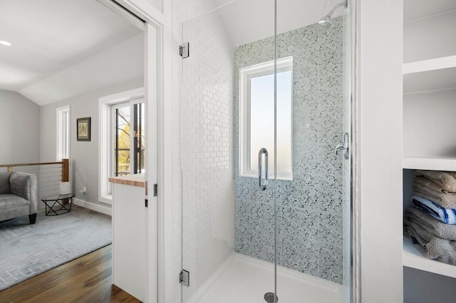 bathroom featuring vaulted ceiling, wood finished floors, and a stall shower