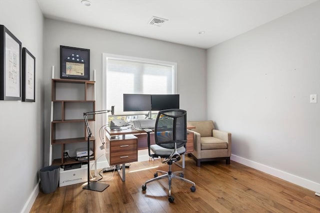 office space featuring baseboards, wood finished floors, and visible vents