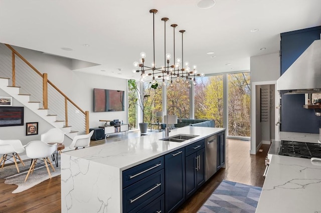 kitchen featuring dark wood-style floors, a center island with sink, a sink, and blue cabinets