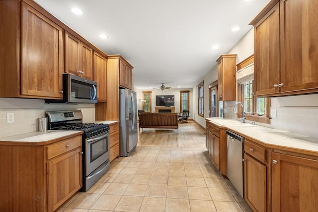 kitchen featuring appliances with stainless steel finishes, backsplash, ceiling fan, light countertops, and a sink