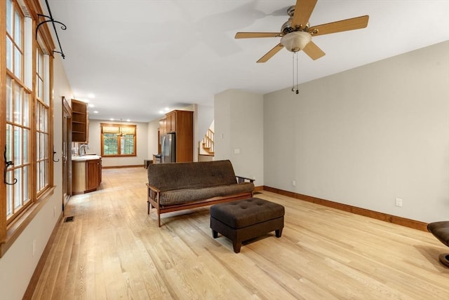 living room with baseboards, stairs, light wood-style floors, and visible vents