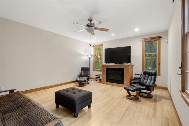 living room featuring wood finished floors, baseboards, ceiling fan, a glass covered fireplace, and recessed lighting