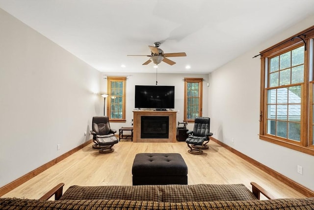 living area featuring wood finished floors, recessed lighting, ceiling fan, baseboards, and a glass covered fireplace