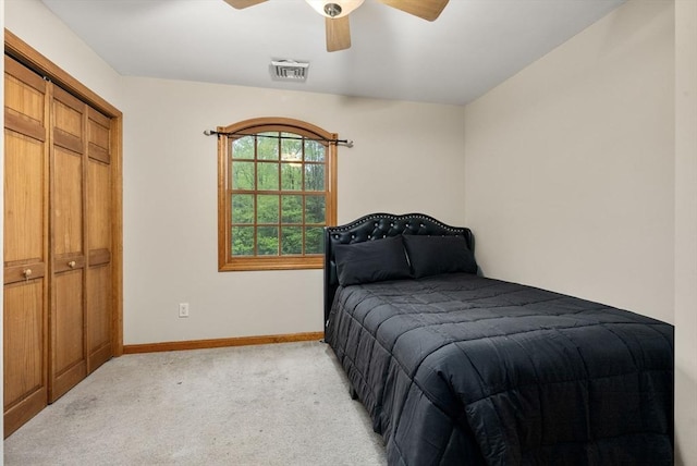 bedroom featuring light colored carpet, baseboards, ceiling fan, and a closet