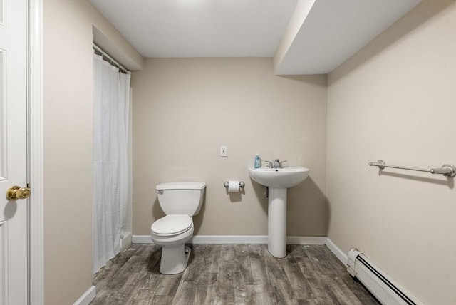 bathroom featuring toilet, baseboards, wood finished floors, and a baseboard radiator