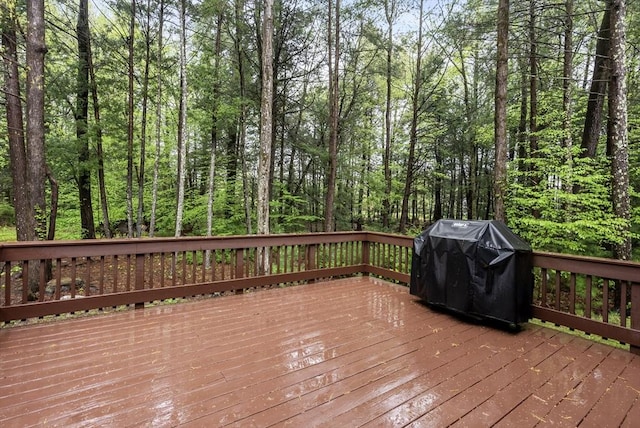 wooden terrace with a forest view and area for grilling