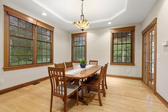 dining space with light wood finished floors, a raised ceiling, baseboards, and recessed lighting