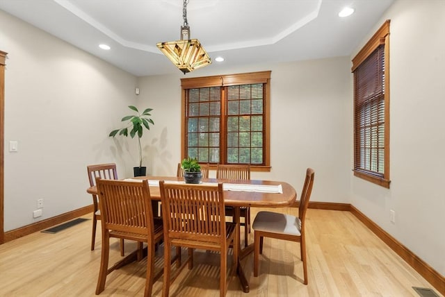 dining area featuring light wood-style flooring, recessed lighting, baseboards, and a tray ceiling