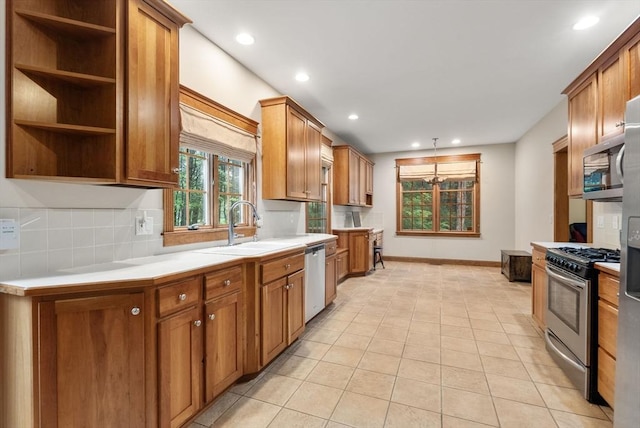 kitchen featuring appliances with stainless steel finishes, a sink, light countertops, brown cabinetry, and recessed lighting
