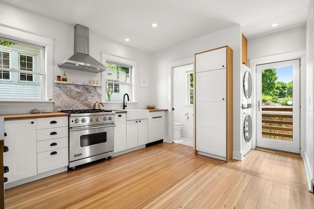 68 Cliftondale St, Boston, MA 02131 - kitchen with luxury stove, stacked washer and clothes dryer, wall chimney range hood, a sink, and light wood finished floors