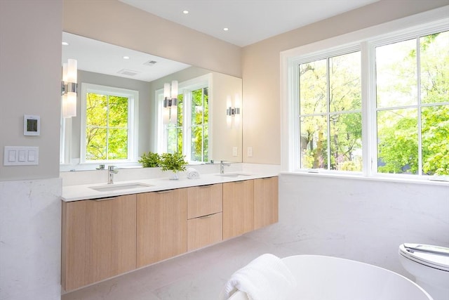 15 Woodcliff Rd, Newton, MA 02461 - bathroom with plenty of natural light, a soaking tub, double vanity, toilet, and recessed lighting
