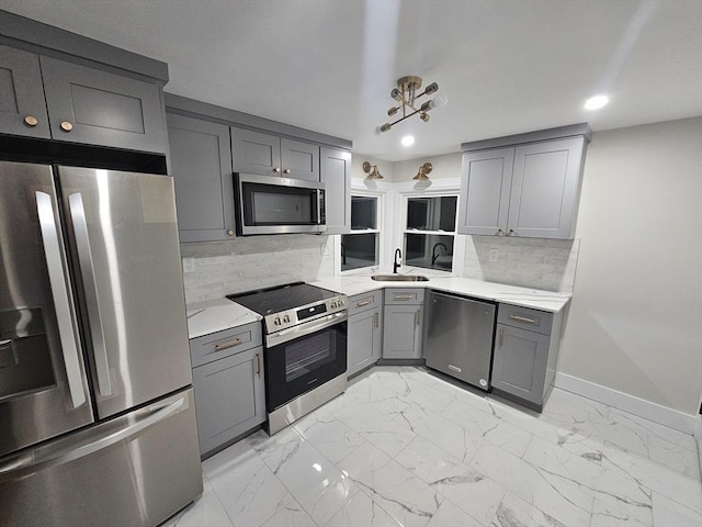 kitchen featuring sink, gray cabinetry, tasteful backsplash, stainless steel appliances, and light stone countertops