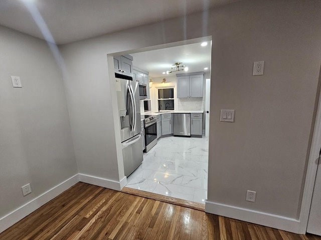 kitchen featuring backsplash, stainless steel appliances, sink, and gray cabinetry