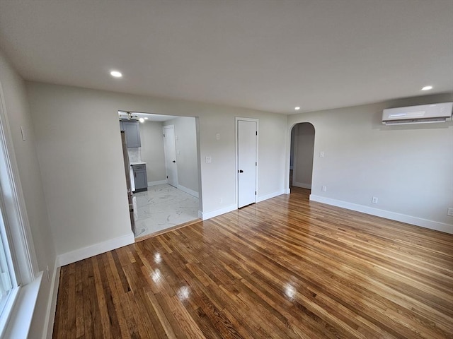 empty room featuring light wood-type flooring and a wall unit AC