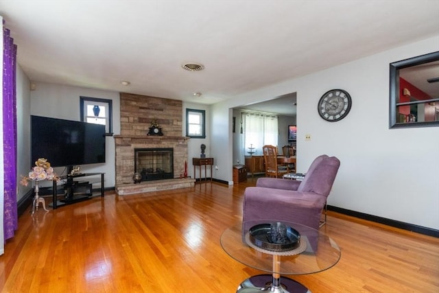 living room featuring plenty of natural light, wood finished floors, a fireplace, and baseboards