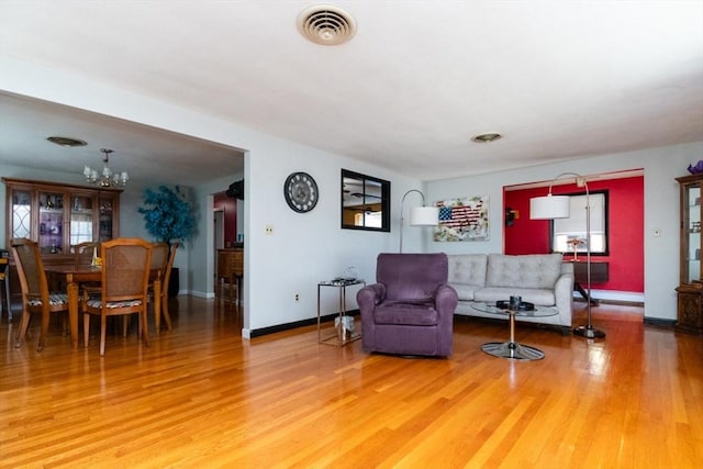 living room featuring wood finished floors, a chandelier, and baseboards