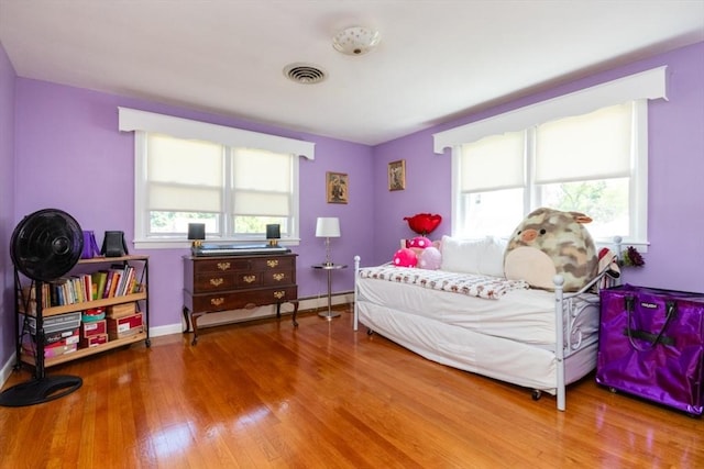 bedroom featuring wood finished floors, baseboards, and a baseboard radiator