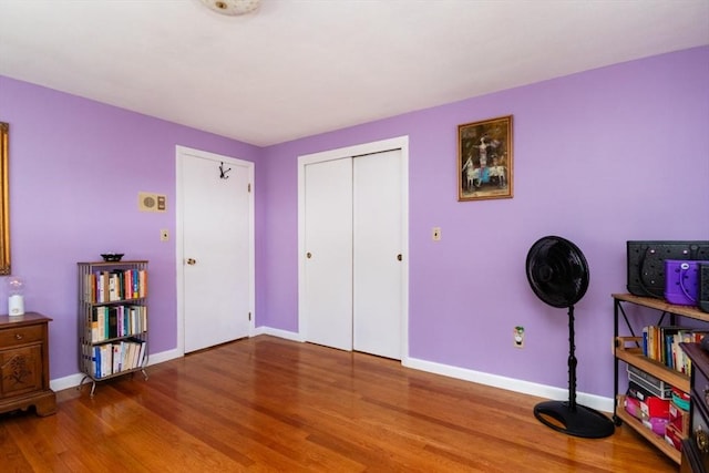 bedroom featuring wood finished floors, baseboards, and a closet