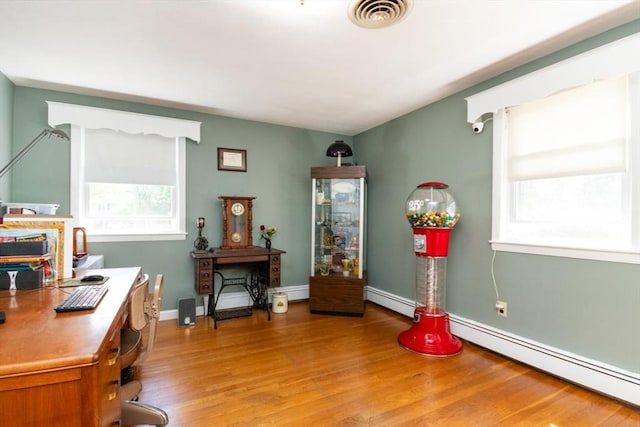 office area with healthy amount of natural light, light wood-style flooring, a baseboard radiator, and baseboards