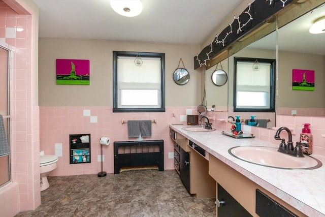 full bath featuring tile walls, healthy amount of natural light, an enclosed shower, toilet, and wainscoting