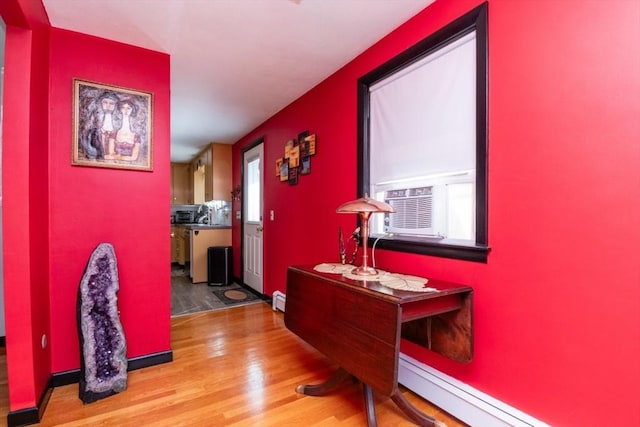 hall featuring wood finished floors, a baseboard radiator, a baseboard heating unit, cooling unit, and baseboards