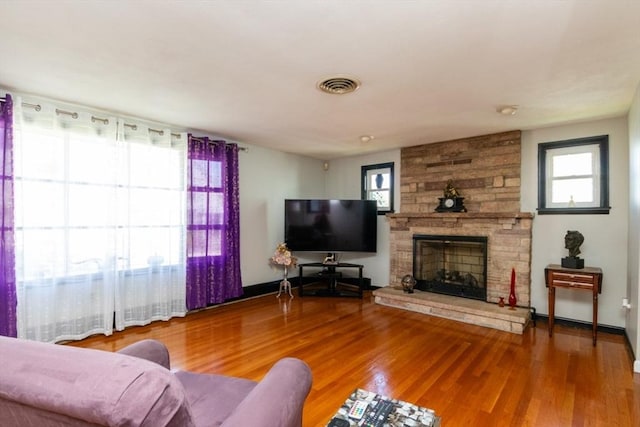 living area featuring a fireplace, wood finished floors, and baseboards