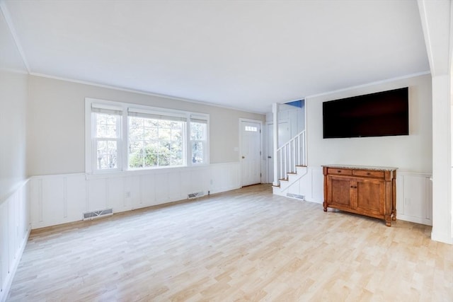 unfurnished living room featuring light wood-type flooring and ornamental molding