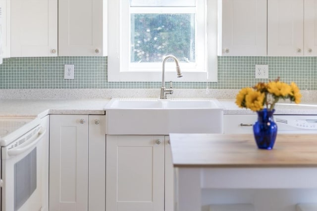 kitchen featuring decorative backsplash, white range with electric cooktop, white cabinetry, and sink