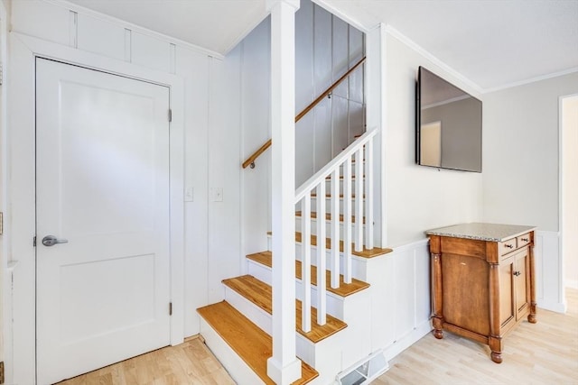 staircase with hardwood / wood-style floors and ornamental molding