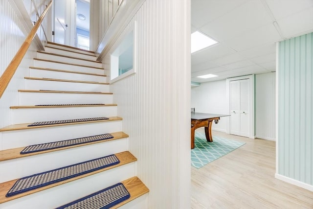 stairs featuring hardwood / wood-style floors and a drop ceiling