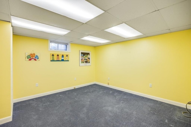 empty room featuring dark colored carpet and a drop ceiling