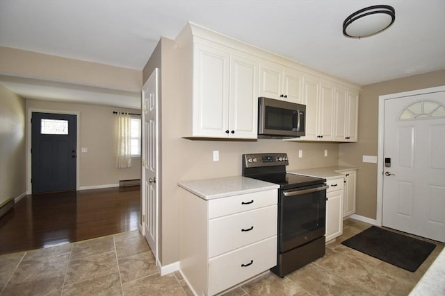 kitchen featuring black electric range, light wood-type flooring, white cabinets, and a baseboard radiator