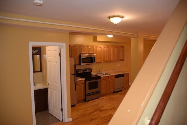 kitchen featuring appliances with stainless steel finishes, light hardwood / wood-style floors, and sink