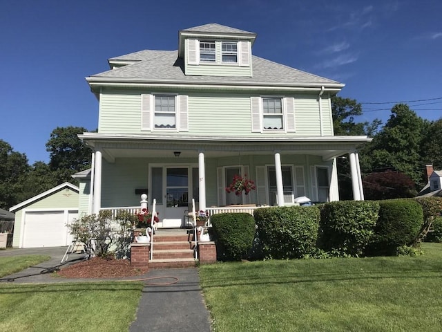 view of front of property with a front lawn, a garage, and an outbuilding