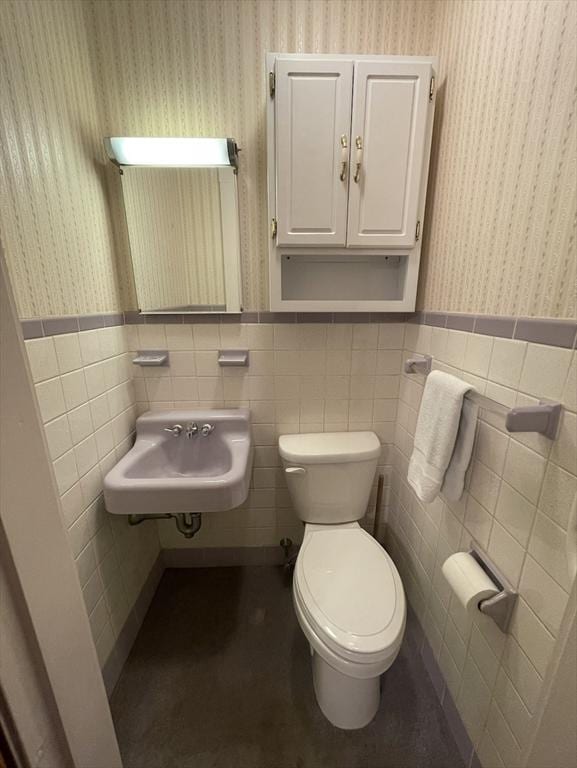 bathroom with toilet, tile walls, and sink